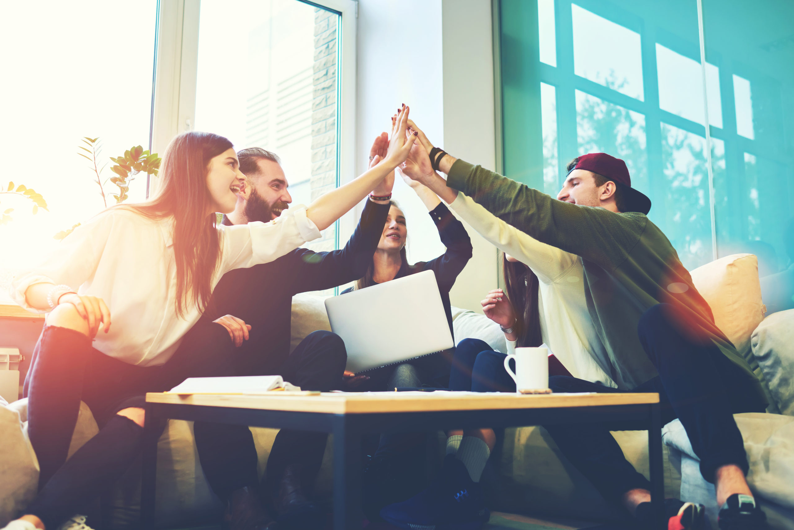 group of five young adults giving all a high five