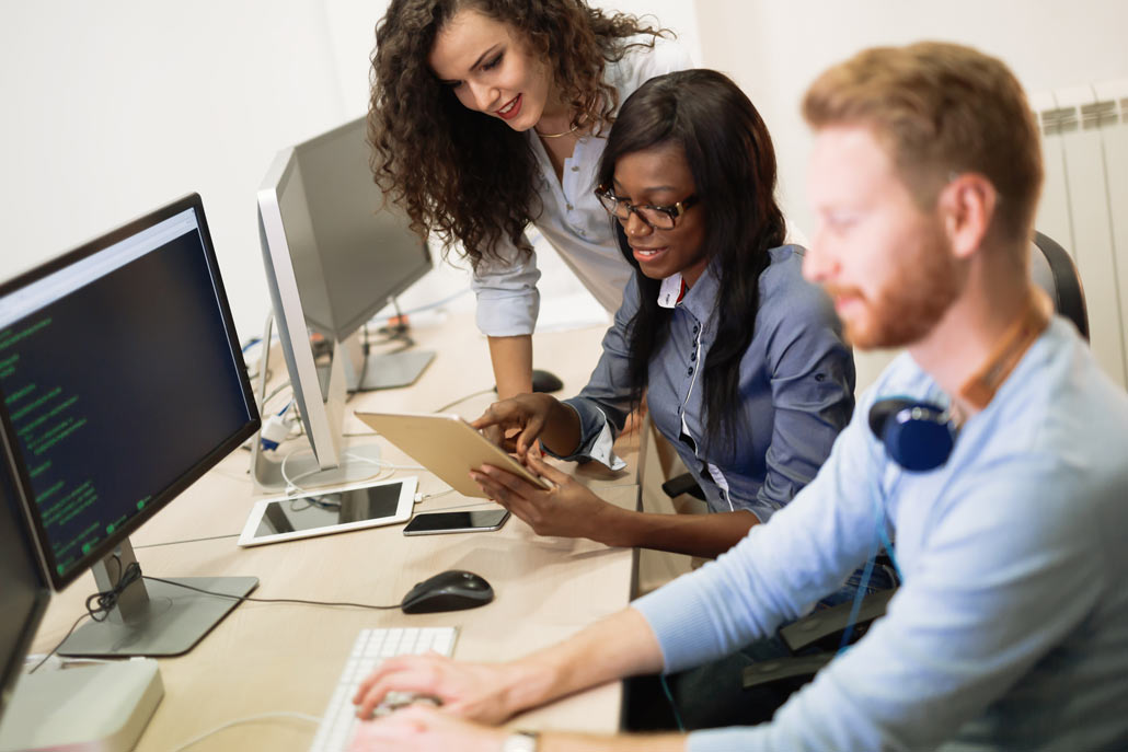 three young people working on a computer and tablet