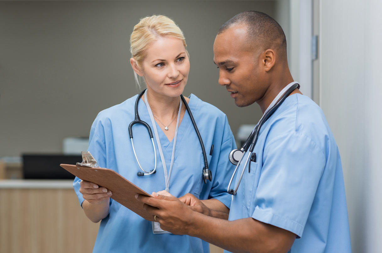 a woman nurse and male nurse looking at a clipboard