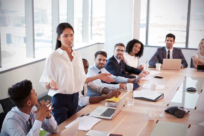 Woman standing and speaking to a group of people in a business meeting